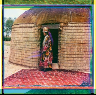 Jeune femme turkmène debout de profil, devant une yourte, portant vêtements et bijoux traditionnels, [automne 1911]